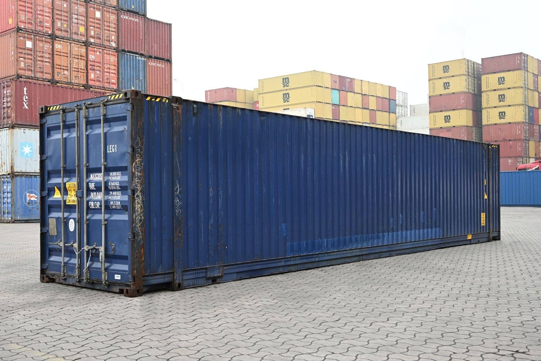 Ein blauer 45 Fuß Container in Schrägansicht vor gestapelten Containern